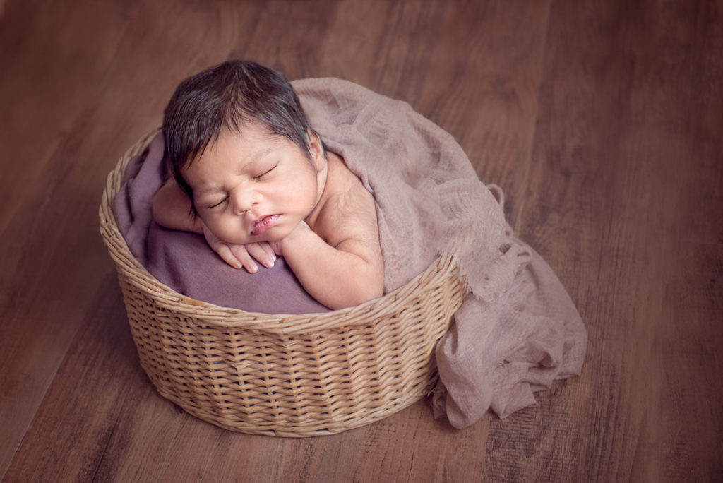 dark moody photo of baby in basket